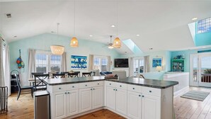A spacious kitchen with white cabinets, a large island, and a dining area with a table and chairs.