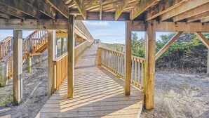 A wooden boardwalk with railings, leading to a covered area with a view of the surrounding landscape. - Graves Cottage - 6 Bedroom Oceanfront Cottage w/Walkway to Beach (Southern Shores)