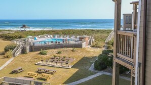 A beachfront property with a pool, outdoor seating, and a view of the ocean. - Just Duck Inn - Bright, Cheerful, 2BR/2BA Semi-Oceanfront condo in Duck, Sleeps 4-7 (Duck)