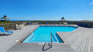 A wooden deck with a pool, lounge chairs, and a view of the ocean. - Just Duck Inn - Bright, Cheerful, 2BR/2BA Semi-Oceanfront condo in Duck, Sleeps 4-7 (Duck)