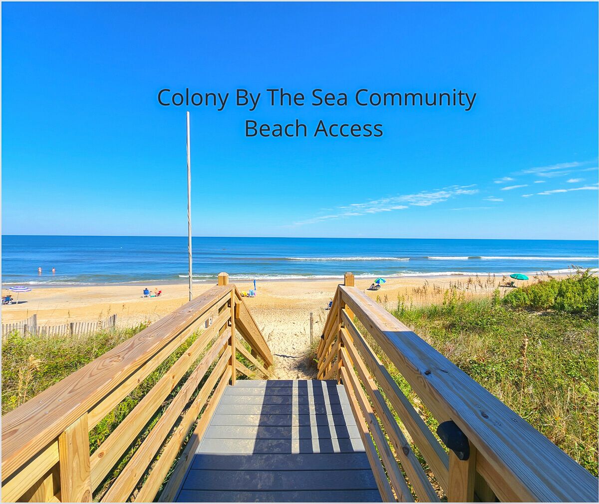 A wooden boardwalk leading to a beach with clear skies and calm waters.