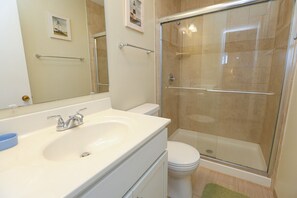 Une salle de bain équipée d’un lavabo, de toilettes et d’une douche à parois de verre.