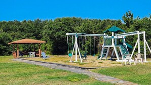 A playground with swings, a slide, and a covered seating area. - Parzanese -  Semi-Oceanfront 1 BR/2BA condo in Duck (Duck)