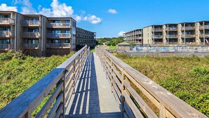 A wooden boardwalk leading to a beachfront residential area with multi-story buildings. - Parzanese -  Semi-Oceanfront 1 BR/2BA condo in Duck (Duck)
