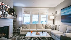 A living room with a sofa, coffee table, fireplace, and large windows. - 2 Br Seneca Condo 200 Beautiful Vista Views (Snowshoe)
