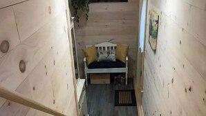 A wooden staircase leading to a room with a bed, a plant, and a painting on the wall.