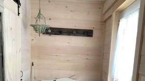 A small, cozy room with a wooden bench, a hanging light fixture, and a door with a window.