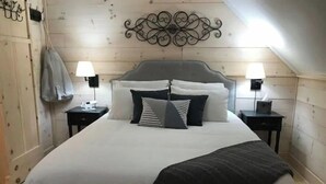 A neatly made bed with a gray headboard, two bedside tables with lamps, and a decorative wall piece above the bed.