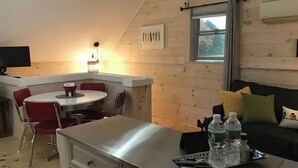 A cozy cabin interior with a dining area, a sofa with cushions, and a tray with water bottles.