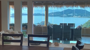 Un salon moderne doté d’une grande porte vitrée donnant sur un balcon qui offre une vue panoramique sur la côte.