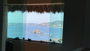Une chambre avec une grande fenêtre donnant sur un paysage côtier.