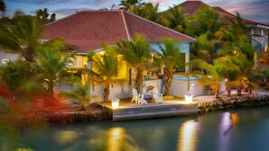 A resort with a pool, palm trees, and a building with a red-tiled roof.