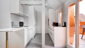A compact kitchen with white cabinetry, a microwave, and a coffee maker. - Chic Vorstädte 2.5 Room w/ W/D & Storage, 2 min to Market, by Blueground (Basel)