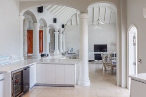A spacious living area with a large kitchen, white columns, and a ceiling fan.