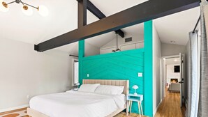 Ein modernes Schlafzimmer mit einem großen Bett, einer Wand in Türkis und einem Holzboden.