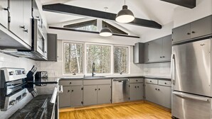 Eine moderne Küche mit Edelstahlgeräten, grauen Schränken und Holzboden.