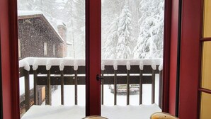 Blick durch ein Fenster mit Holzwertung auf eine verschneite Landschaft.