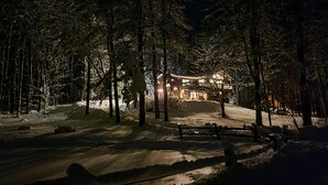 Ein verschneiter Wald mit einem beleuchteten Blockhaus.