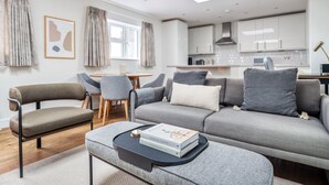 A modern living room with a grey sofa, two armchairs, a coffee table, and a dining area with a wooden table and chairs. - Stylish Marylebone 2BR nr Underground, by Blueground (London)