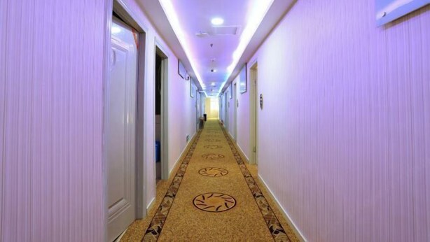 A long hallway with a carpet featuring circular patterns, white walls, and doors on both sides. - Jinpeng Hotel (Guangzhou Yongqingfang Chenjiaxuan Subway Station) (Guangzhou)