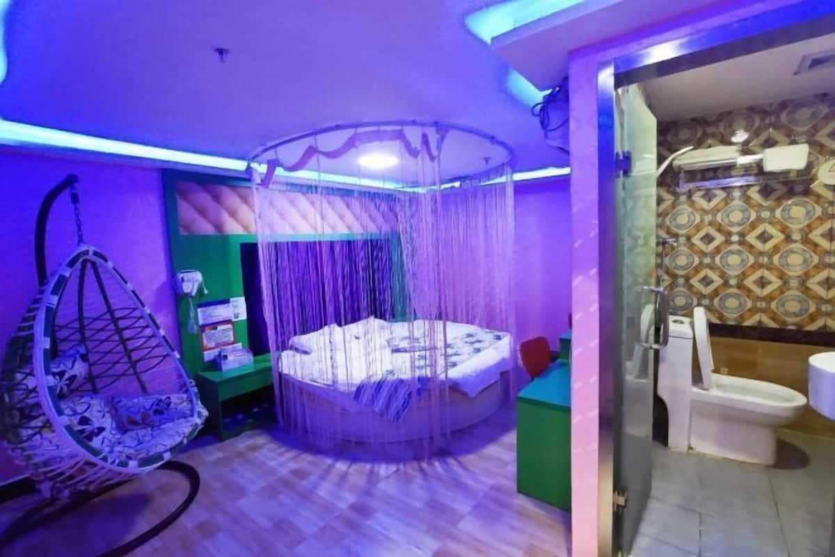A room with a hanging chair, a circular bed with a canopy, and a small table with a chair.