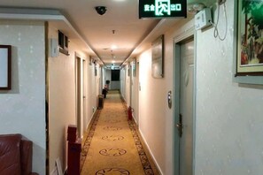 A hotel hallway with a carpeted floor, doors on both sides, and a security camera on the ceiling. - Jinpeng Hotel (Guangzhou Yongqingfang Chenjiaxuan Subway Station) (Guangzhou)