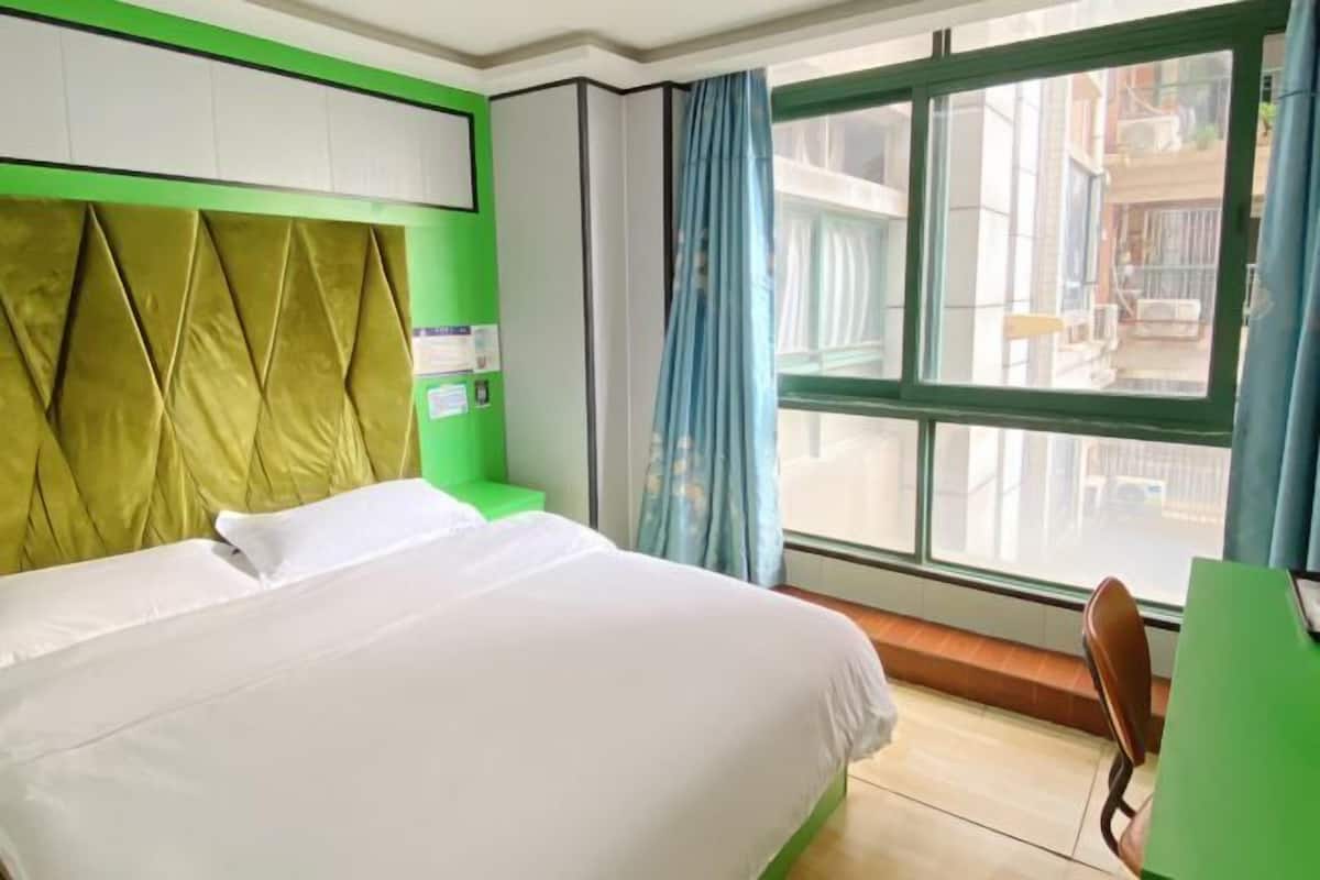 A hotel room with a bed, a desk, and a window with curtains.