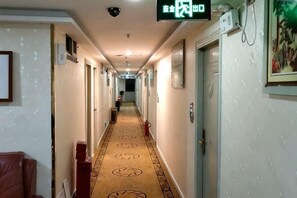 A hotel hallway with a patterned carpet, doors, and a security camera.