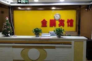 A reception desk with a clock, potted plants, and a sign in a foreign language.