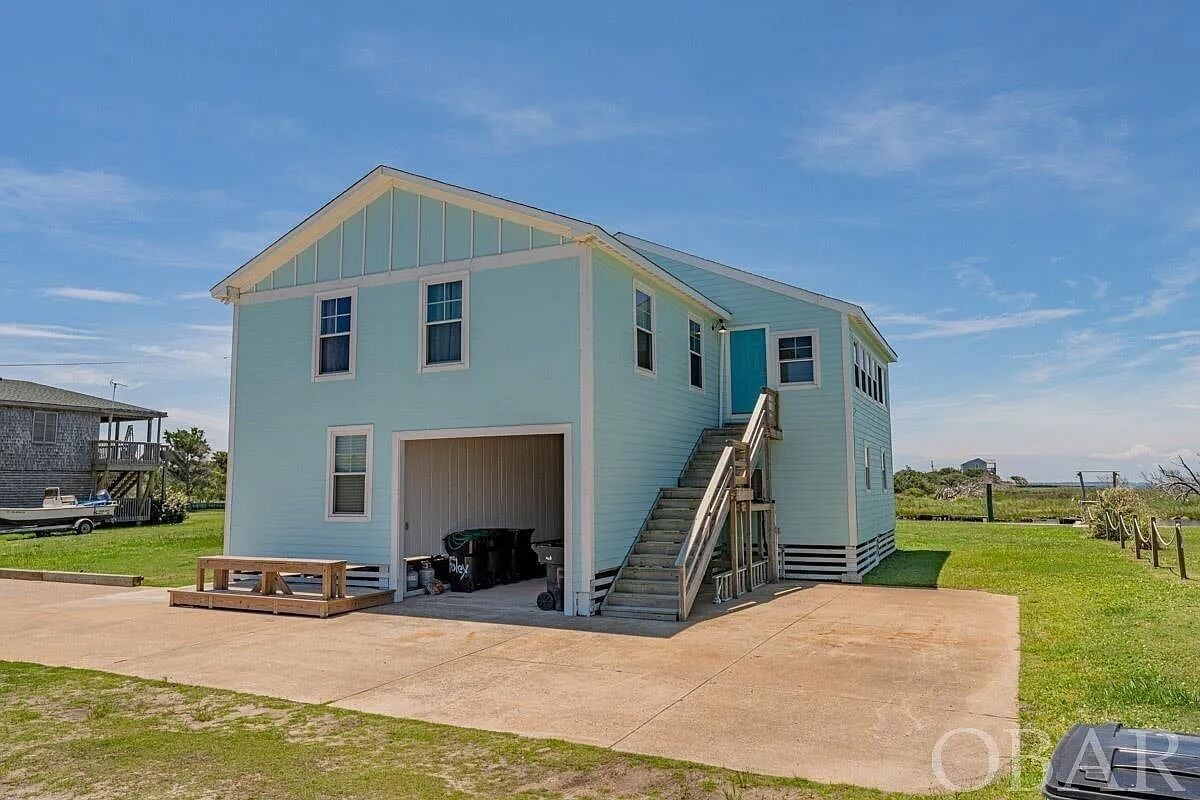 A light blue single-story house with a front garage, a staircase, and a small porch area.