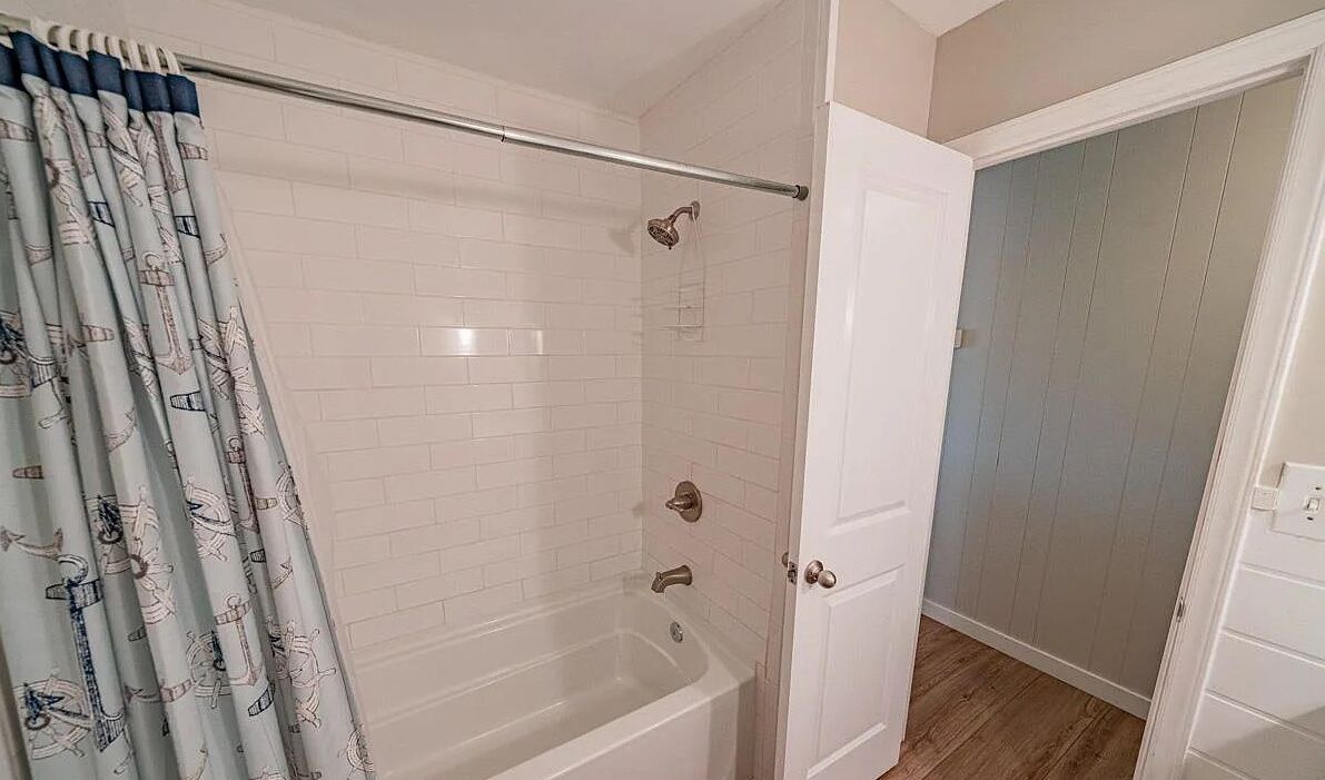 Ein Badezimmer mit Dusche, Badewanne und einer Tür zu einem weiteren Raum.