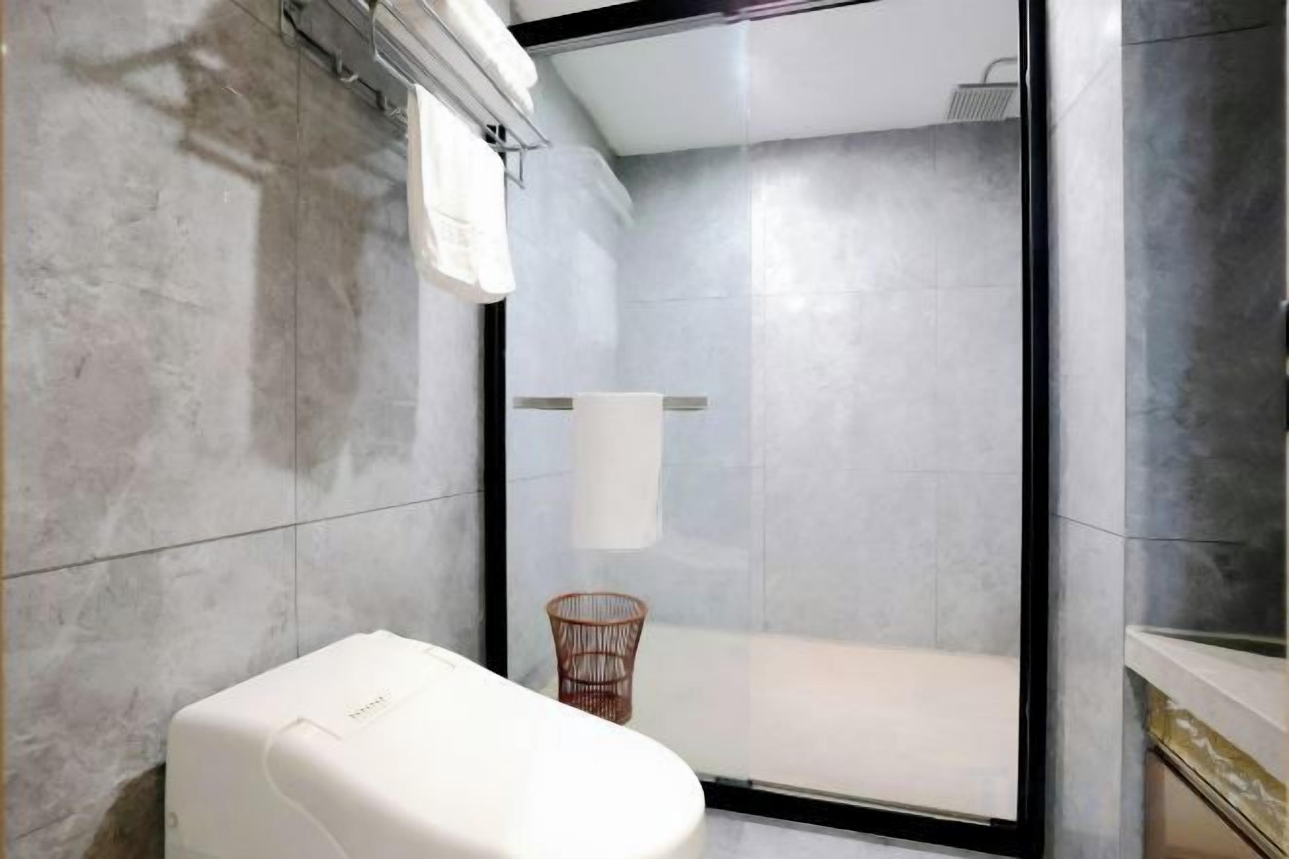 A bathroom with a toilet, a shower, and a towel rack.