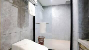 A bathroom with a toilet, a shower, and a towel rack.