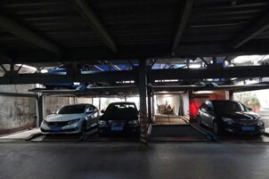 Un estacionamiento techado con tres coches aparcados.
