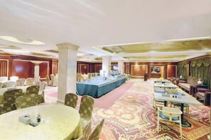 A hotel conference room with round tables, a long table with a blue tablecloth, and a carpeted floor. - Haolilai Grand Hotel (Sanming No.1 High School) (Sanming)