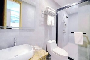 Uma casa de banho moderna com cabine de duche em vidro, sanita branca e bancada de mármore.