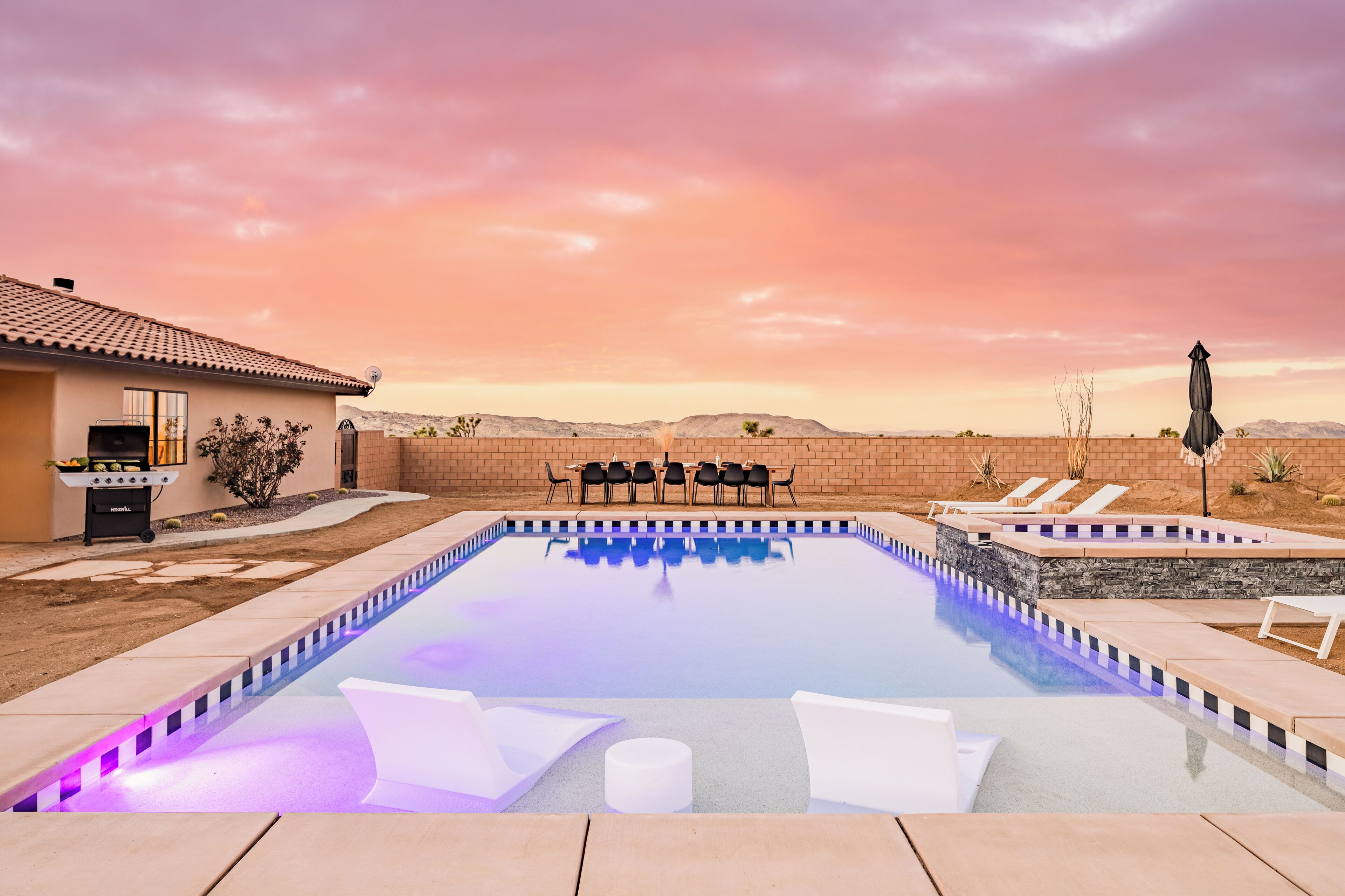 Una piscina con sillas de descanso, zona de barbacoa y vistas al paisaje desértico.