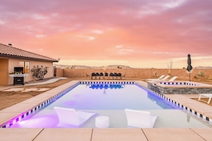 Una piscina con sillas de descanso, zona de barbacoa y vistas al paisaje desértico.
