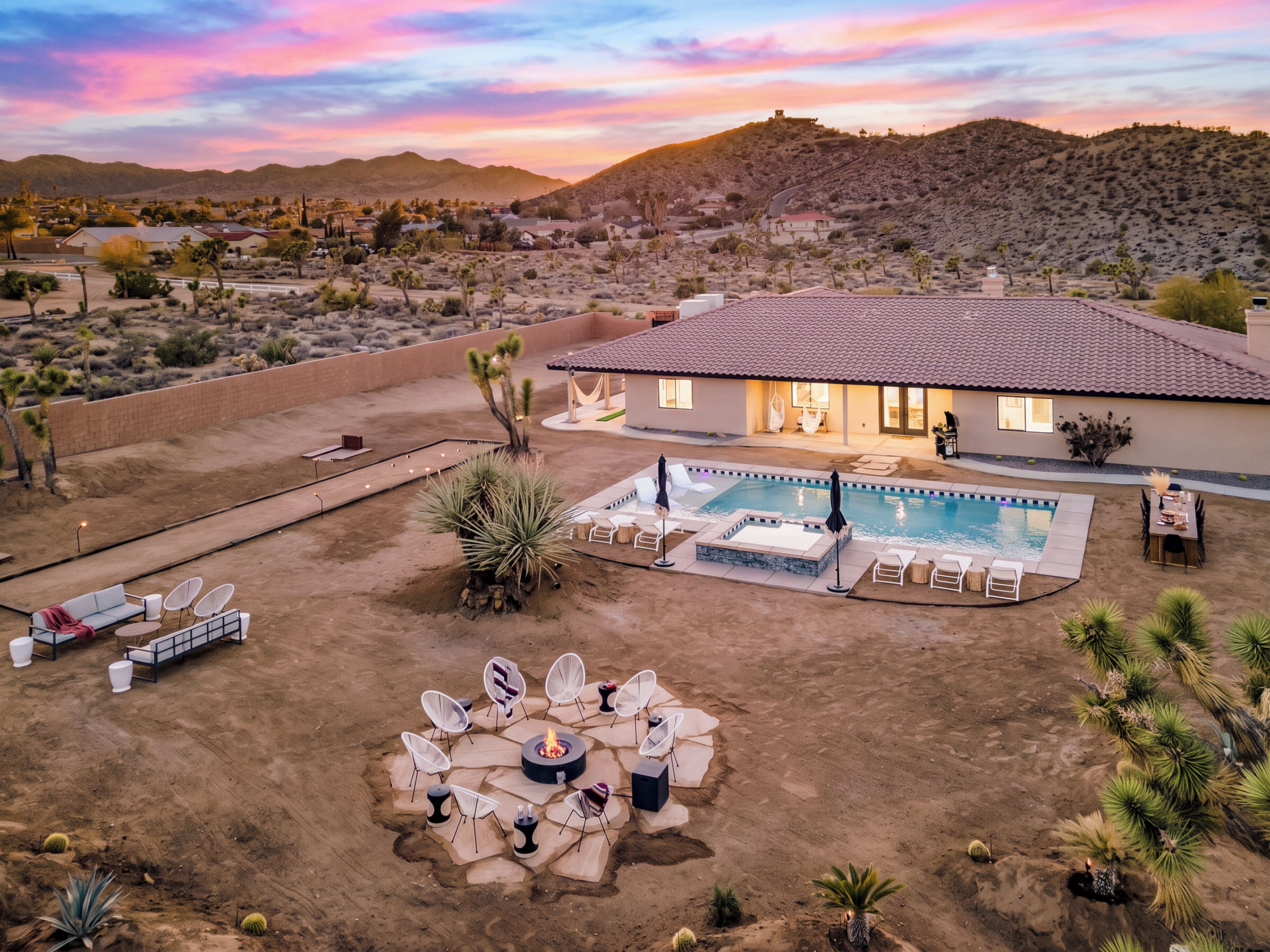 A residential property with a swimming pool, outdoor seating area, and a fire pit.