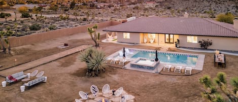 A residential property with a swimming pool, outdoor seating area, and a fire pit.