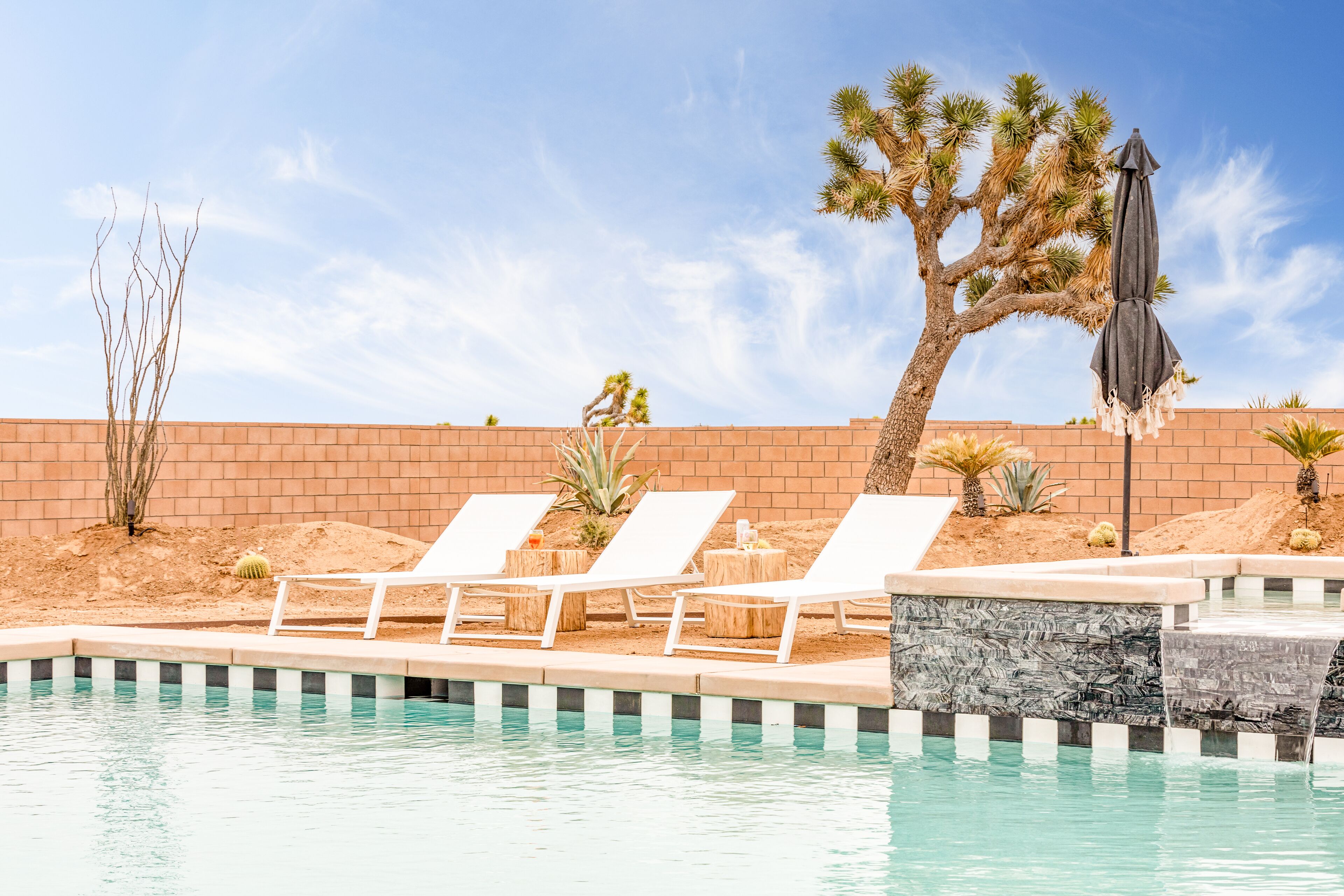 Un área de piscina con sillas de descanso y una palmera.