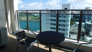 A balcony with a table and chairs, overlooking a body of water and buildings. - buransiera naha akebono puremisuto 1009 (Naha)