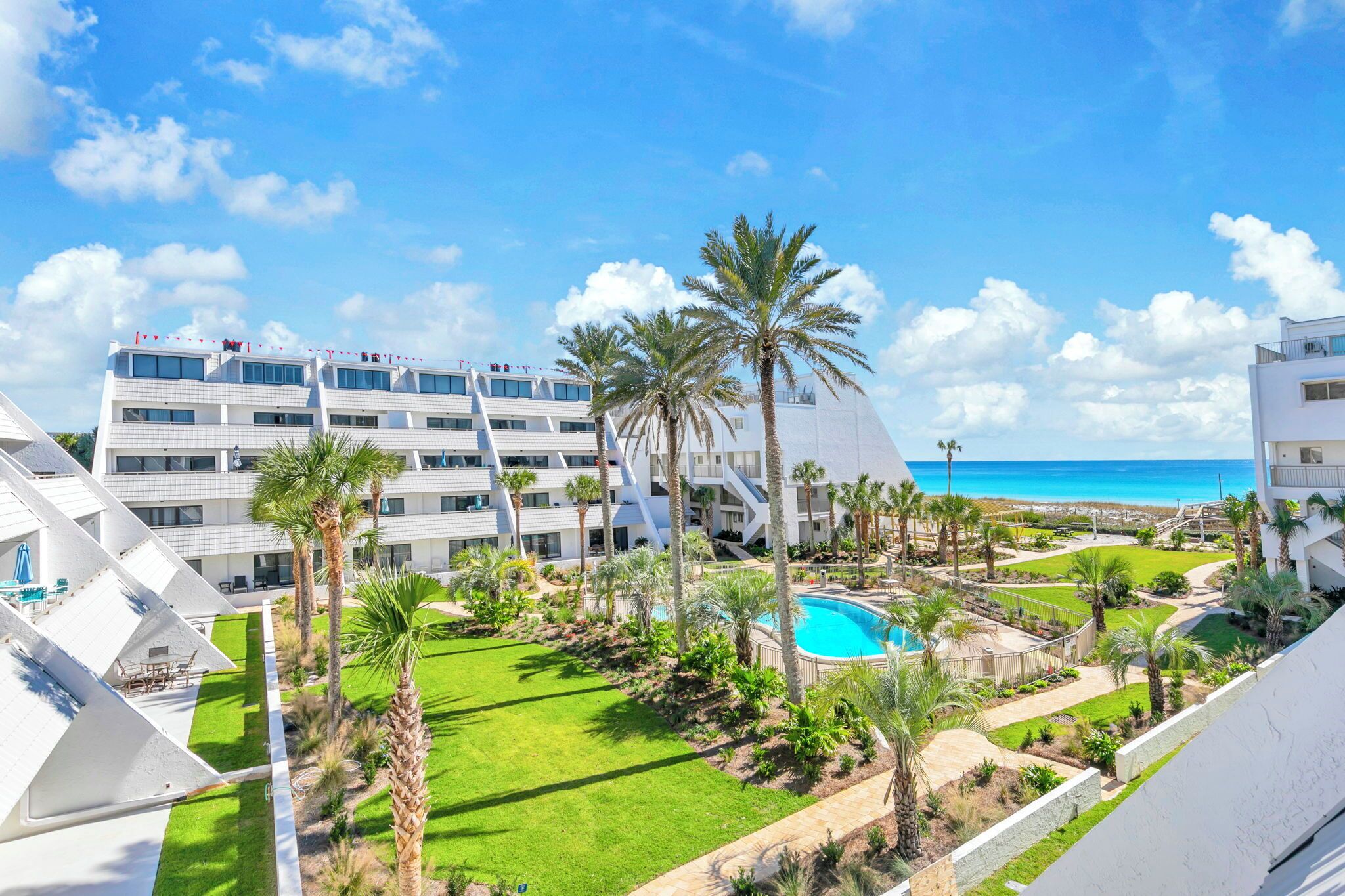 Ein modernes Hotel mit mehreren Etagen, einem Pool und Blick aufs Meer.