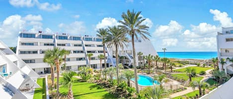 Ein modernes Hotel mit mehreren Etagen, einem Pool und Blick aufs Meer.