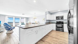A modern kitchen with white cabinets, stainless steel appliances, and a large island.