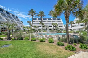 Un hotel con piscina, palmeras y un cielo azul despejado.