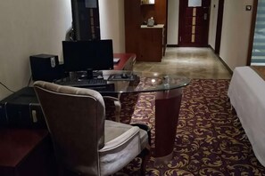 A hotel room with a desk, chair, TV, and a patterned carpet. - Qianhao Hotel (Tongzi County)