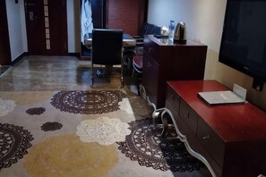 A hotel room with a patterned carpet, a desk with a laptop, a TV, and a cabinet. - Qianhao Hotel (Tongzi County)