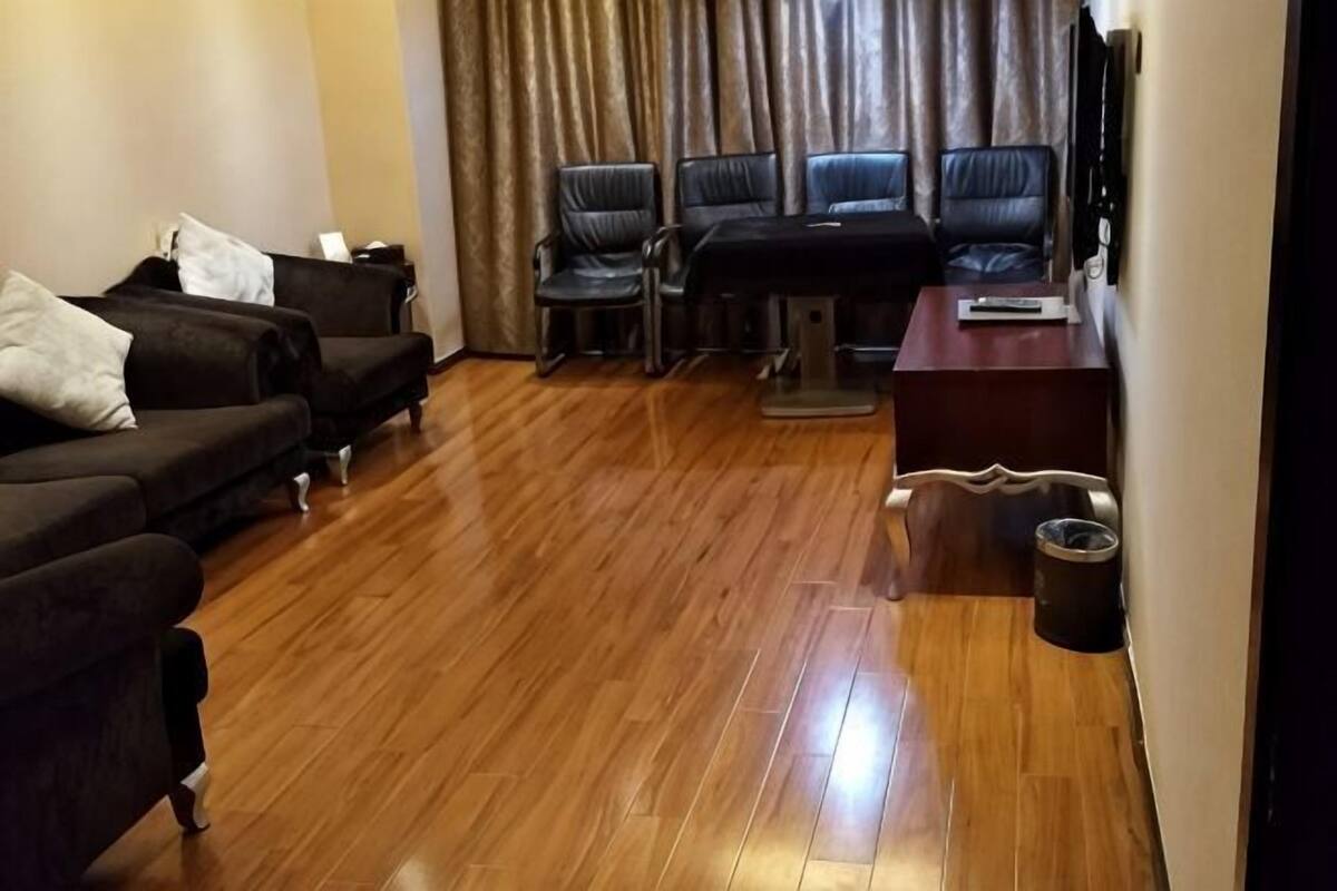 A living room with a wooden floor, a sofa set, a coffee table, and a TV.