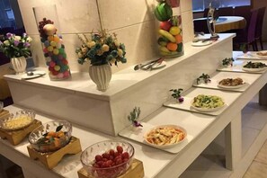 Una mesa de buffet con diversos alimentos y centros de mesa decorativos.
